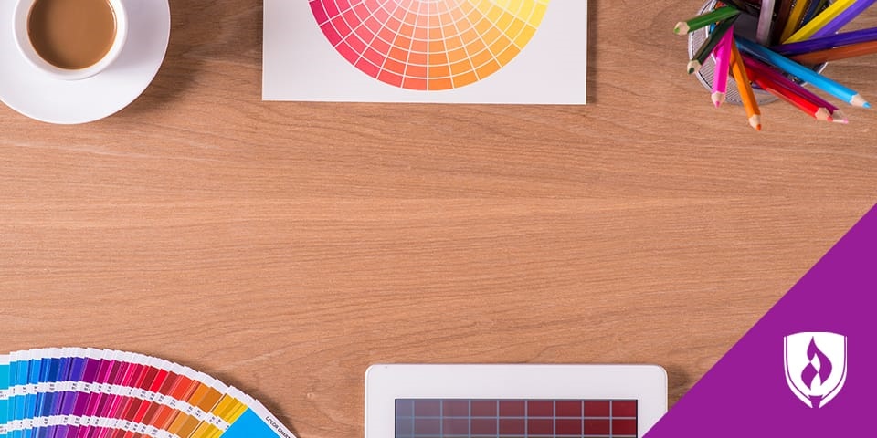 photo of a desk with colored pencils, color wheel, and a coffee