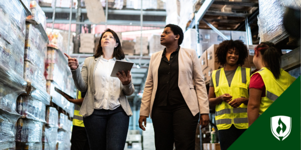 Two female managers walk through a warehouse discussing plans