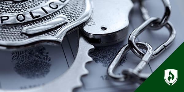 justice studies become a police officer blog M Photograph of a badge resting on top of a pair of handcuffs.