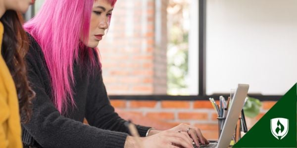 A manager with pink hair researches something on their computer