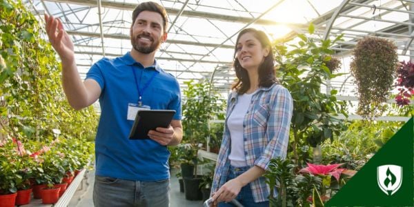 A retail worker helps a customer in a greenhouse