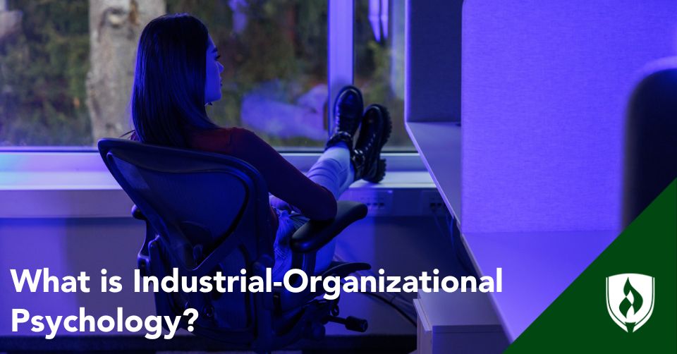 What is IO psychology header A business professional sits at a desk in purple light
