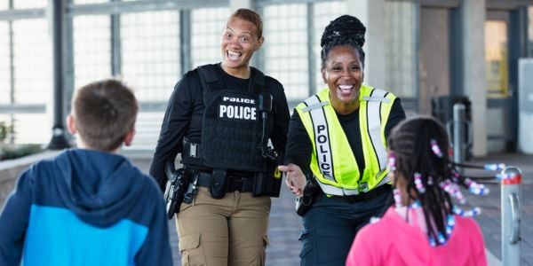 Two police officers in different uniforms greet children