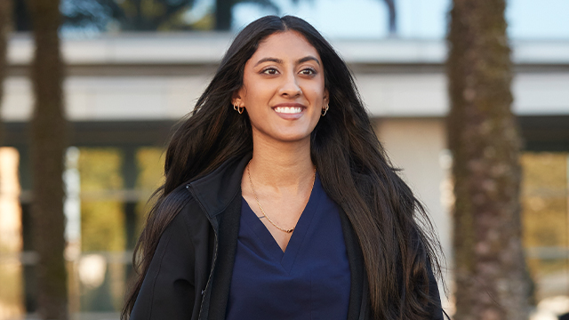 Smiling nursing student in dark blue scrubs outside